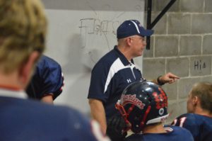 Photo/ Katie Berrell  A sneak peek into the football team’s halftime meeting shows coach, Jeff Weiland, giving his team an inspirational pep talk before taking the field again.  