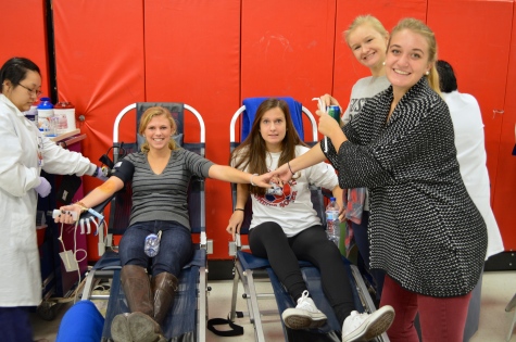 Seniors Kristie Tunheim and Nicole Anderson huddle around their classmates as they begin donating blood.