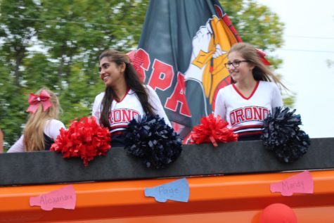 The cheerleaders smile while riding in a dump truck