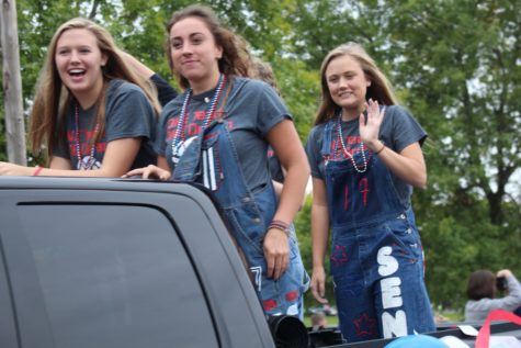 Senior volleyball players wave on the crowd as they drive by in a truck