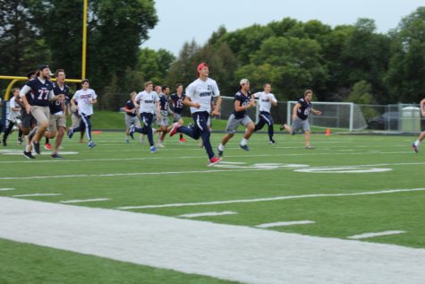 The soccer and football boys run onto the field to meet the girls dance team