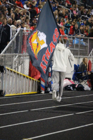 Senior Blake Bren runs across the track with the spartan flag.