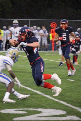 Sophomore quarterback Nick Prentice dodges the defensive line of Holy Angels on Homecoming night.